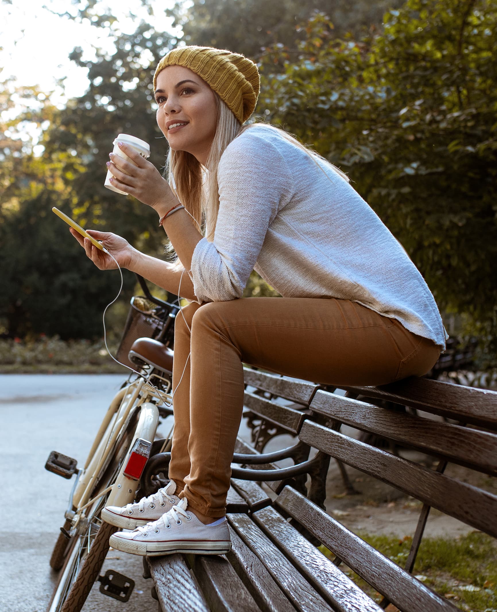 Resident relaxing on a park bench with coffee beside her bicycle at MORE